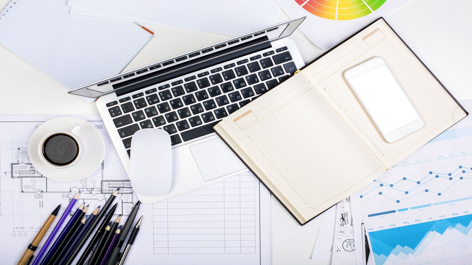 A desk with technical books, a laptop showing cloud architecture diagrams, and handwritten notes
